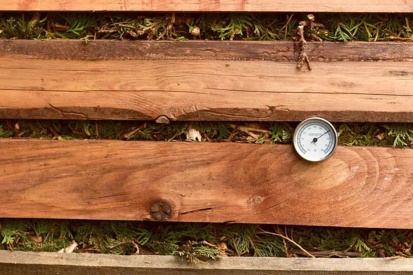 thermometer inside wooden compost bin 