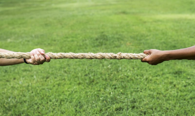 tug of war showing two pairs of hands pulling on rope in a field