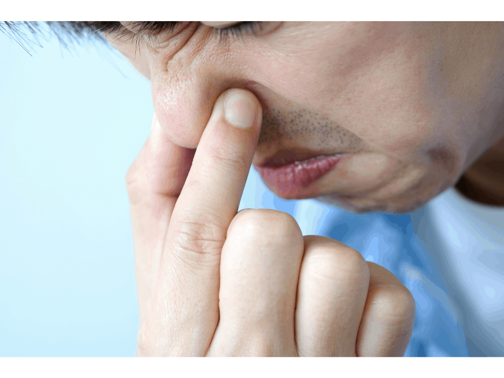man holding nose witha screwed up face indicating a bad smell