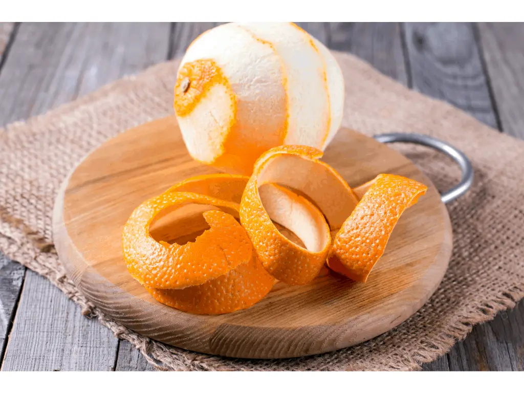 peeled orange with peel next to it on a round wooden tray
