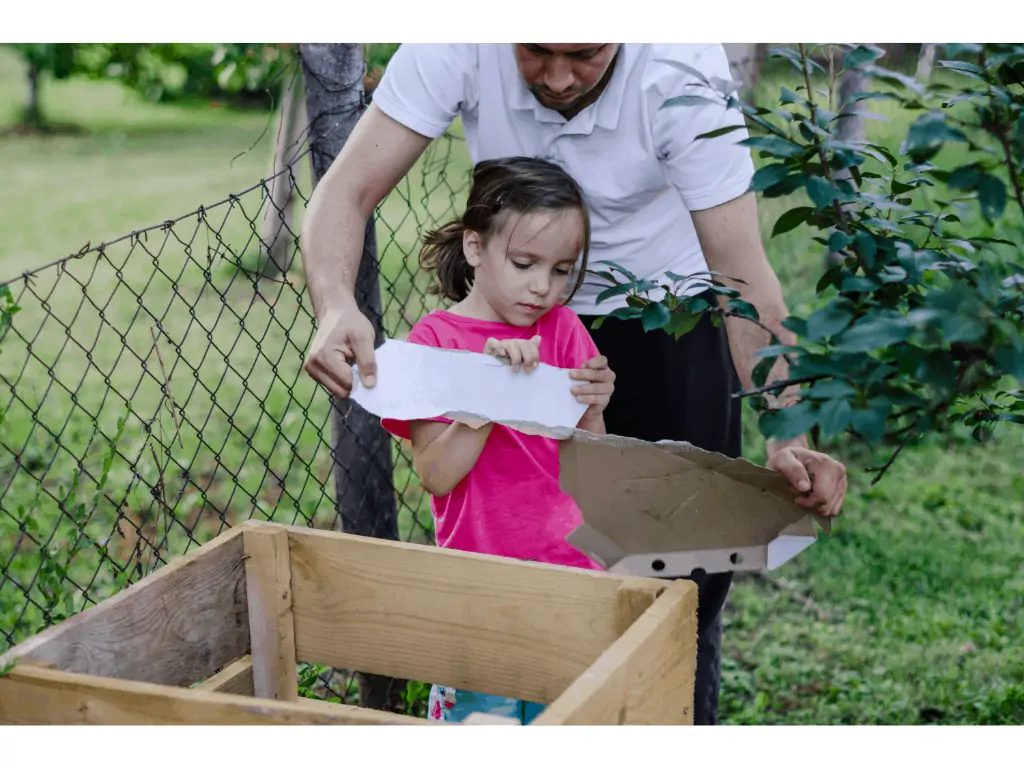 parent with young child putting cardboard into a compost bin